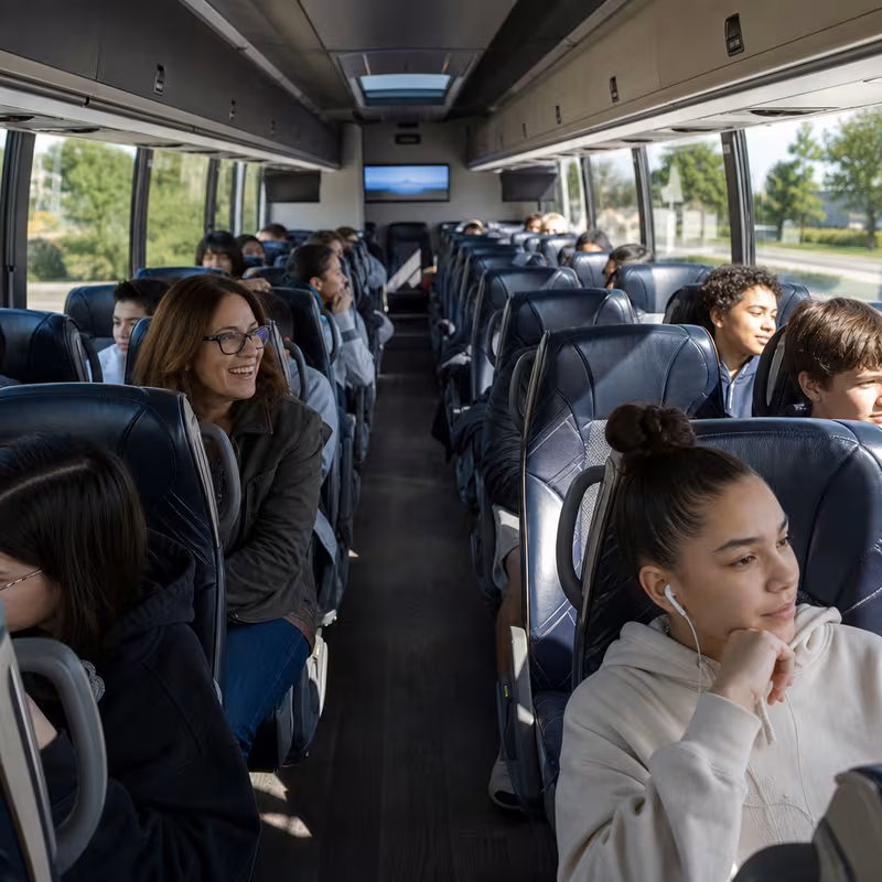 Group boarding a white charter bus for School Transportation transportation in Long Beach